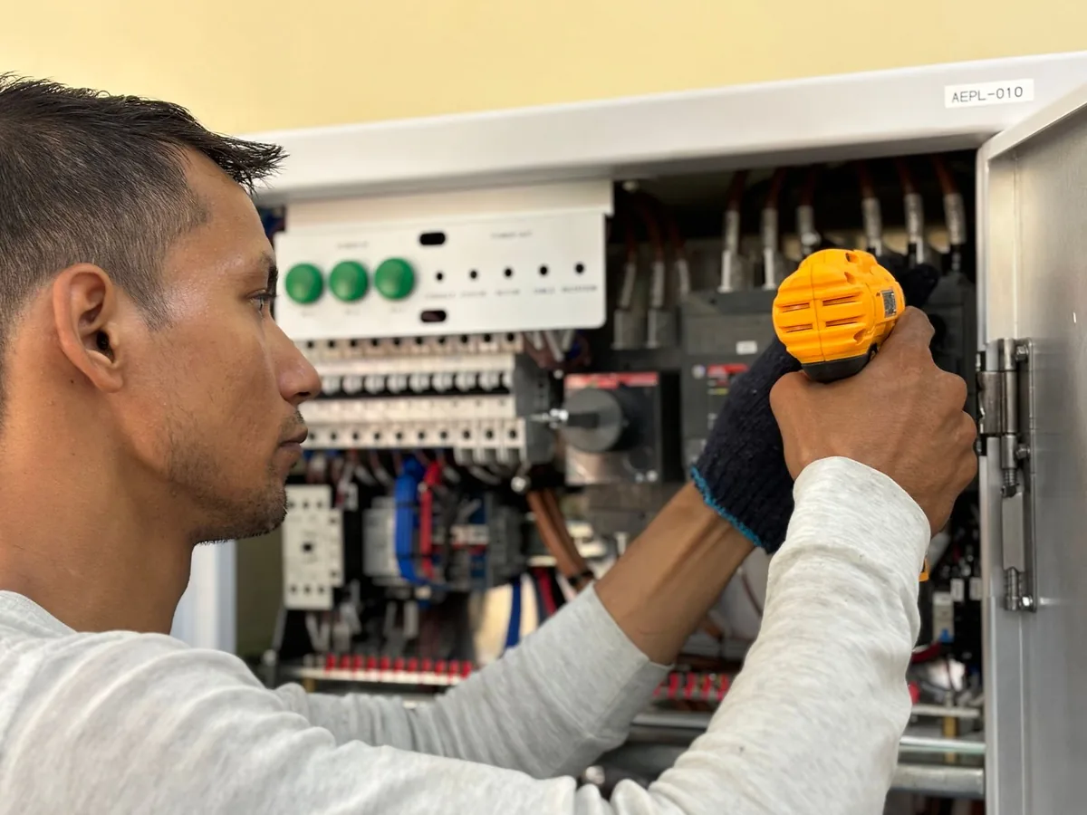 An electrician wiring generator controls inside an electrical panel at an Ossining, NY home